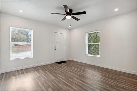 unfurnished room with dark wood-type flooring, plenty of natural light, and ceiling fan