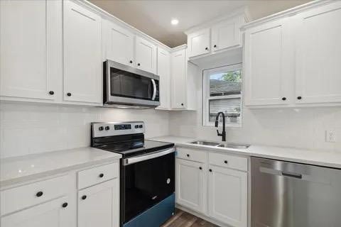 kitchen with appliances with stainless steel finishes, sink, and white cabinets