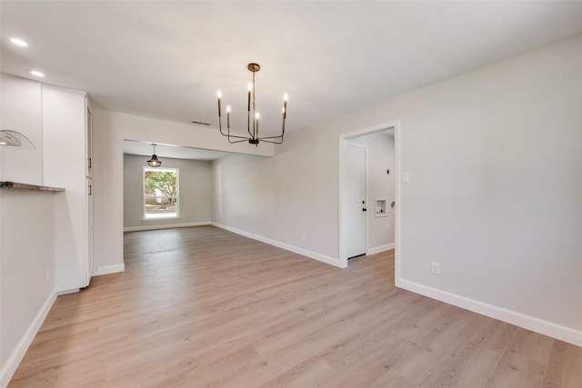 empty room featuring light wood-style floors, baseboards, a chandelier, and recessed lighting