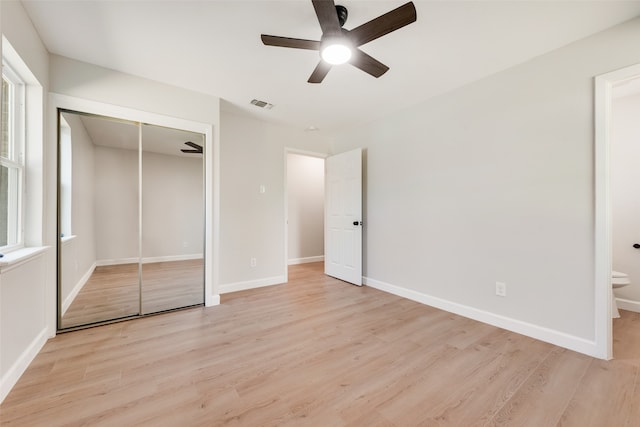 unfurnished bedroom with connected bathroom, light hardwood / wood-style flooring, a closet, and ceiling fan