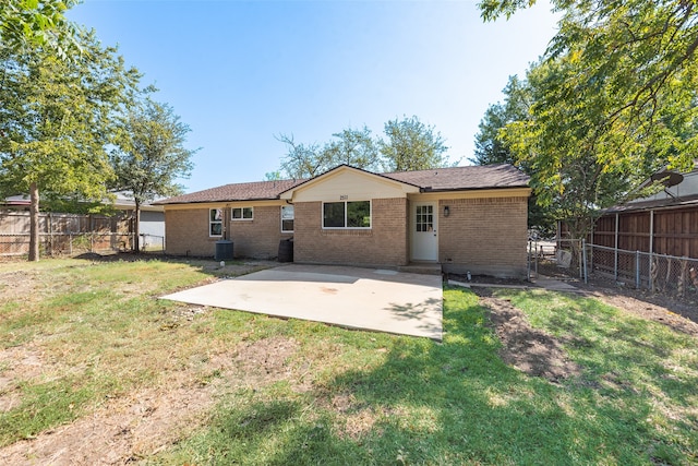 back of house featuring a fenced backyard, a lawn, brick siding, and a patio