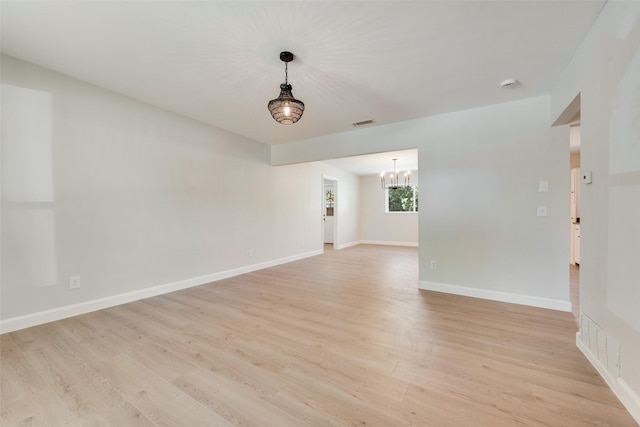 spare room featuring light wood-type flooring, visible vents, and baseboards