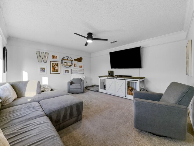 living room featuring ornamental molding, a textured ceiling, carpet flooring, and ceiling fan