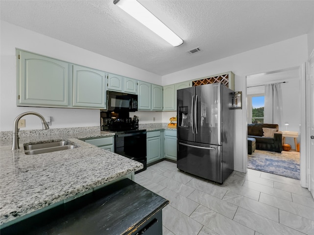 kitchen featuring light stone countertops, a textured ceiling, black appliances, and sink