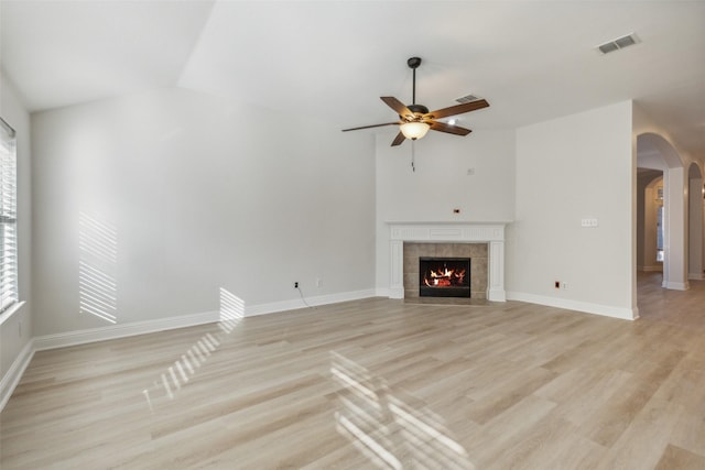 unfurnished living room with a tile fireplace, light hardwood / wood-style flooring, vaulted ceiling, and ceiling fan