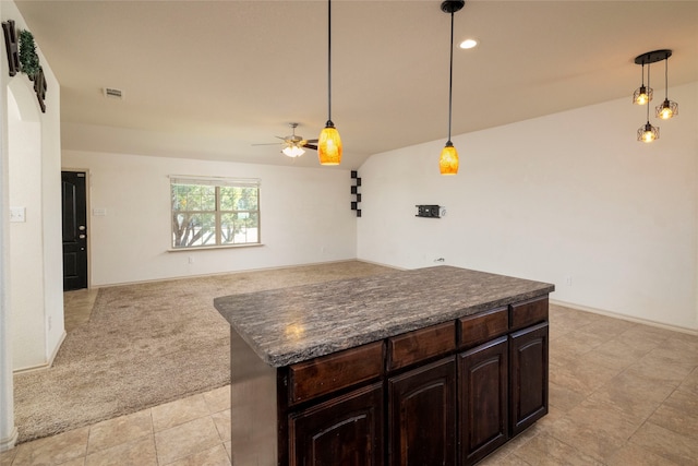 kitchen featuring hanging light fixtures, light carpet, dark brown cabinets, a center island, and ceiling fan