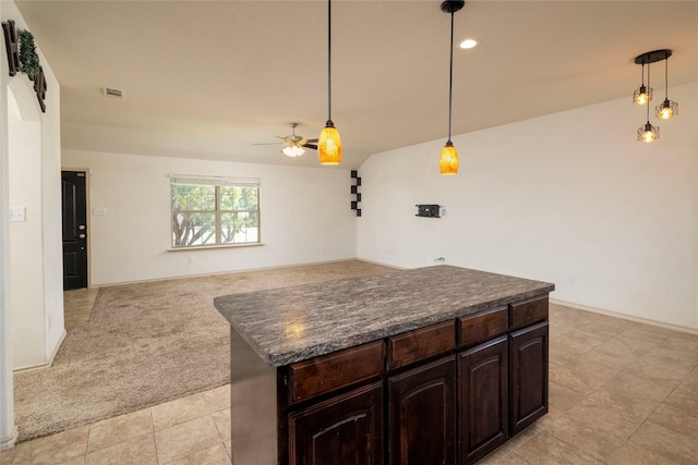 kitchen with dark countertops, dark brown cabinets, visible vents, a ceiling fan, and light colored carpet