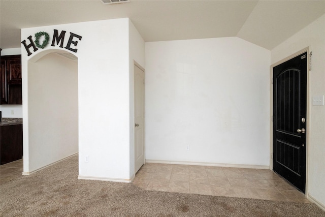 interior space featuring vaulted ceiling, visible vents, and light carpet