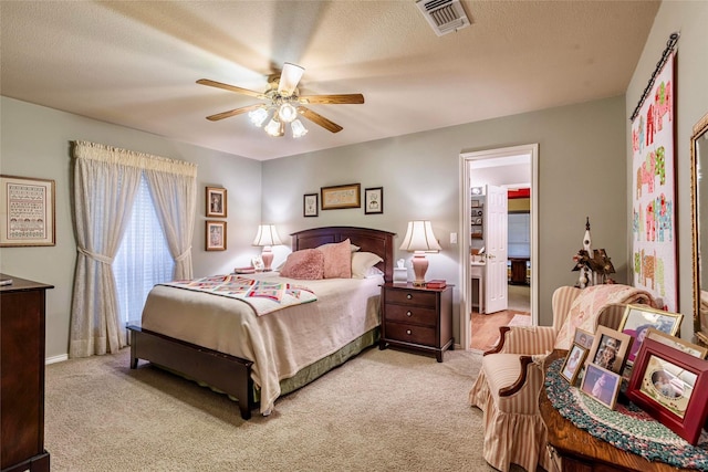 bedroom with ceiling fan, light colored carpet, and a textured ceiling