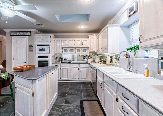 kitchen with a skylight, sink, wall oven, crown molding, and white microwave