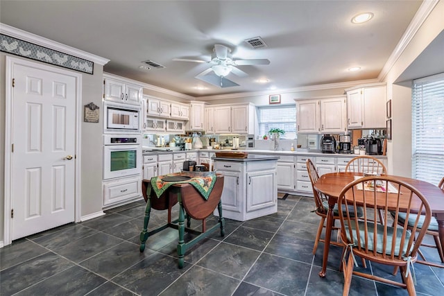 kitchen with white cabinets, a healthy amount of sunlight, white appliances, and crown molding