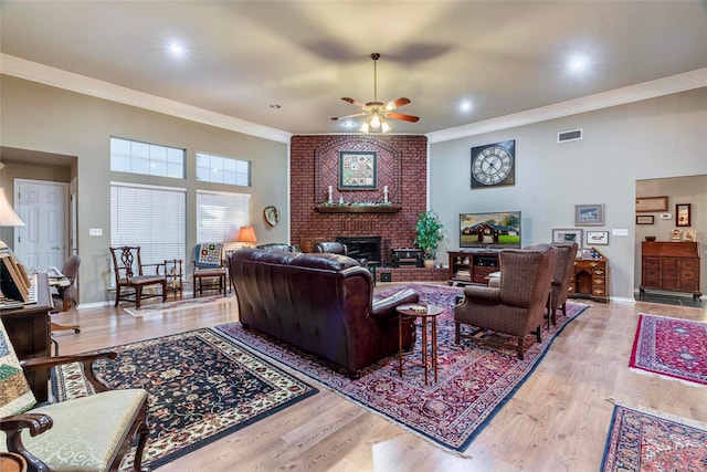 living room featuring ceiling fan, light hardwood / wood-style floors, ornamental molding, and a fireplace