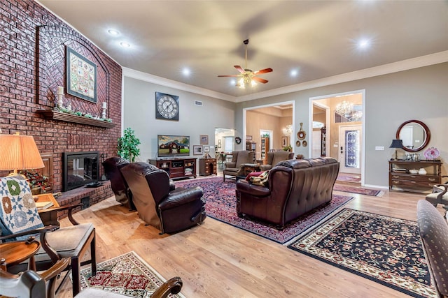 living room with crown molding, a fireplace, ceiling fan, and light hardwood / wood-style floors