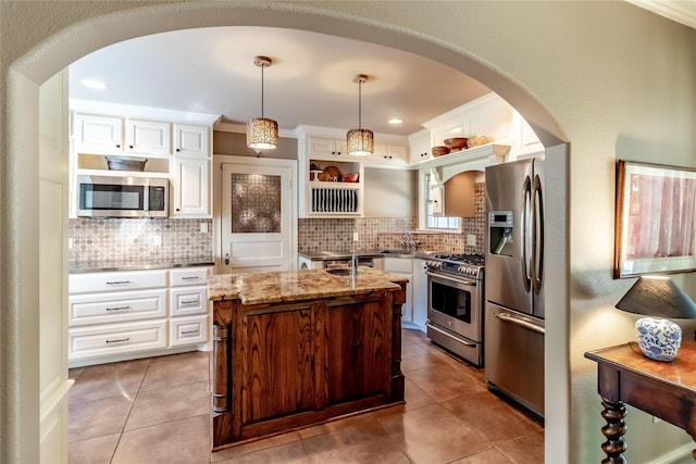 kitchen featuring open shelves, appliances with stainless steel finishes, arched walkways, light stone countertops, and backsplash
