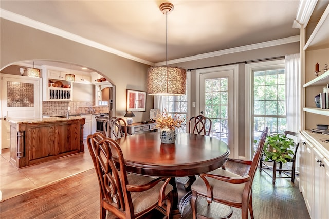 dining room featuring ornamental molding, sink, and light hardwood / wood-style floors