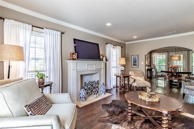 living room with a tiled fireplace, ornamental molding, and dark hardwood / wood-style flooring