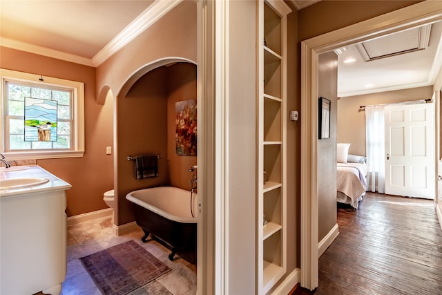 bathroom featuring a bath, toilet, vanity, hardwood / wood-style flooring, and ornamental molding