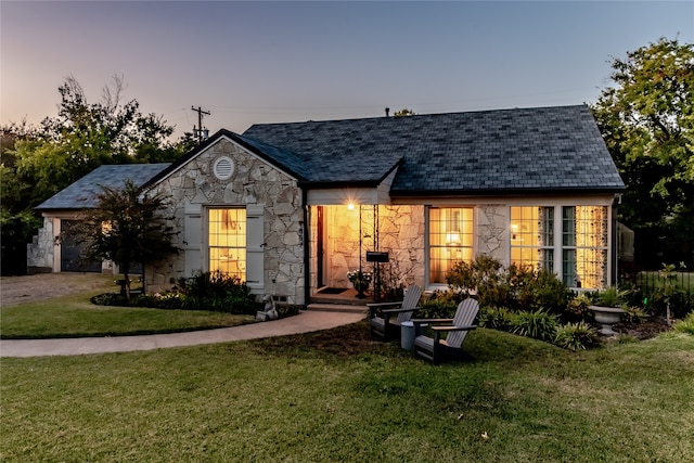 back house at dusk featuring a yard