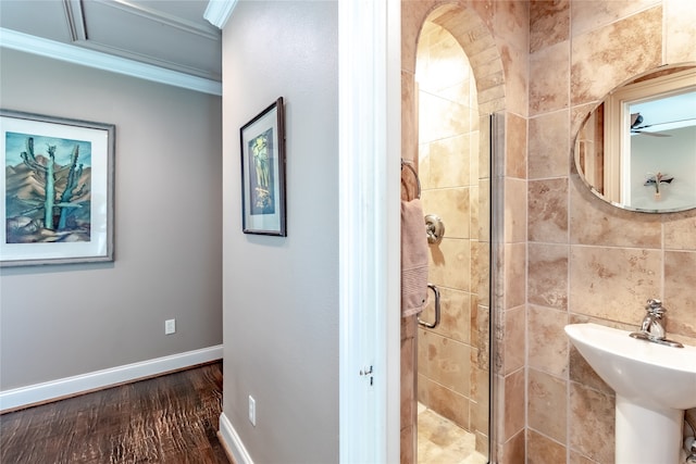 bathroom with sink, an enclosed shower, tile walls, crown molding, and hardwood / wood-style flooring