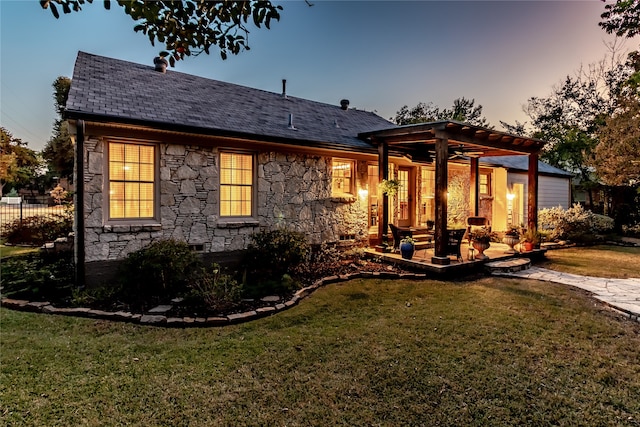 back house at dusk featuring a yard, a patio, and a pergola