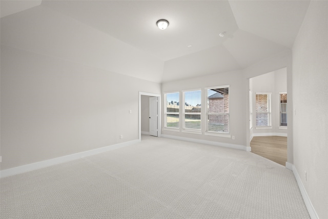 carpeted empty room featuring vaulted ceiling