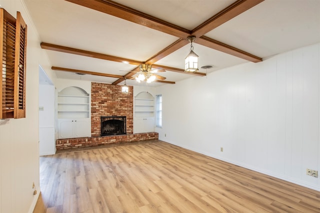 unfurnished living room featuring a fireplace, beam ceiling, light wood-type flooring, and ceiling fan