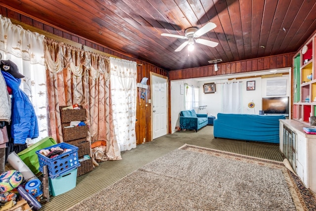 carpeted bedroom with ceiling fan, wood walls, and wooden ceiling