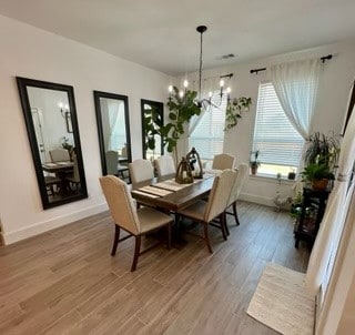 dining area featuring wood-type flooring and a notable chandelier