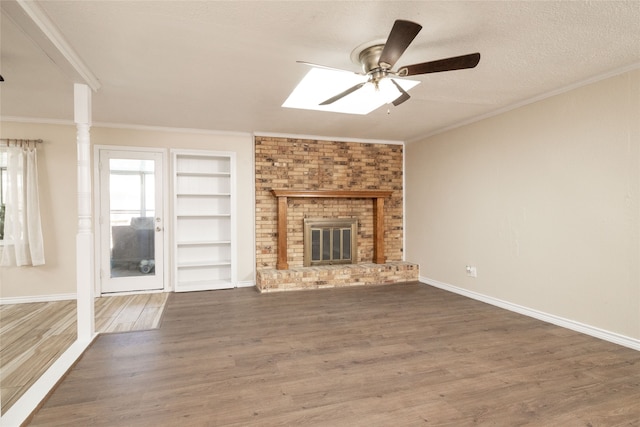 unfurnished living room with crown molding, a brick fireplace, dark hardwood / wood-style flooring, a textured ceiling, and ceiling fan