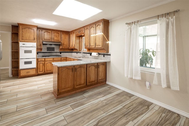 kitchen with sink, kitchen peninsula, black stovetop, crown molding, and white double oven