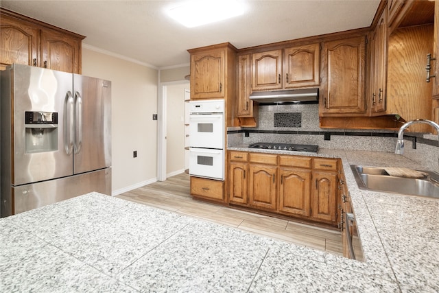 kitchen featuring sink, double oven, gas cooktop, light hardwood / wood-style flooring, and stainless steel refrigerator with ice dispenser