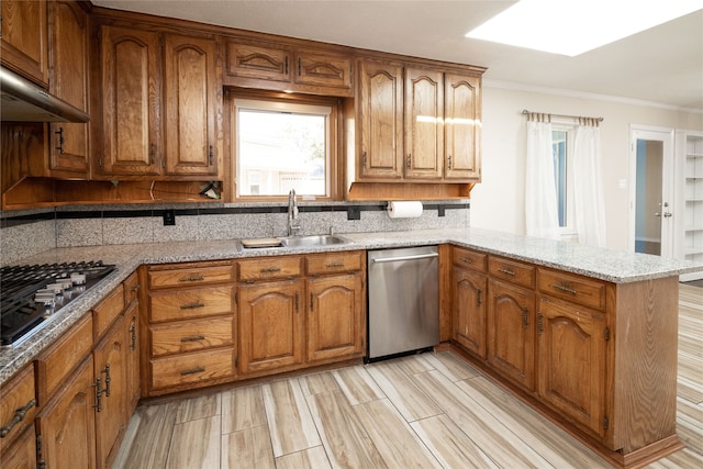 kitchen featuring kitchen peninsula, stainless steel appliances, sink, crown molding, and light stone counters