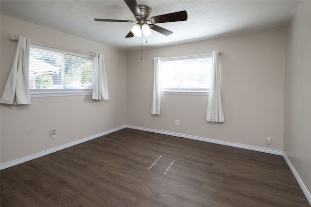 empty room with ceiling fan, plenty of natural light, and dark hardwood / wood-style flooring