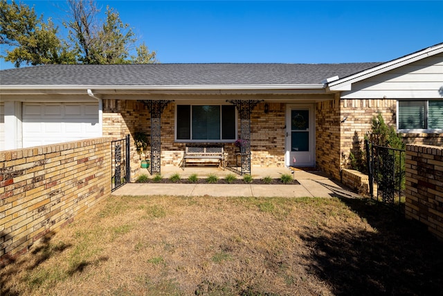 view of front of property featuring covered porch, a garage, and a front lawn