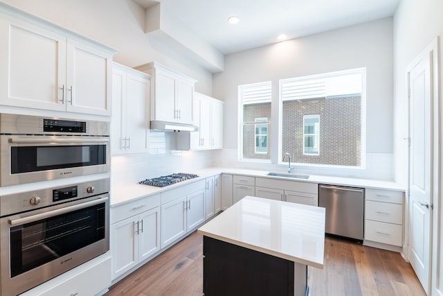 kitchen featuring appliances with stainless steel finishes, sink, light wood-type flooring, and white cabinets