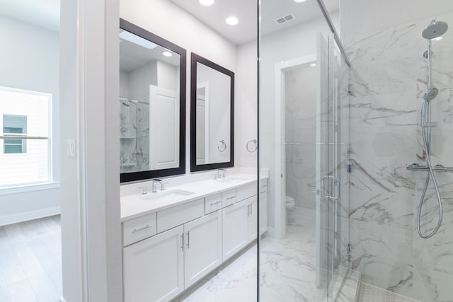 bathroom featuring vanity, a shower with shower door, and toilet