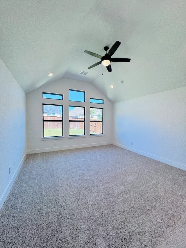 carpeted spare room featuring lofted ceiling, a textured ceiling, and ceiling fan