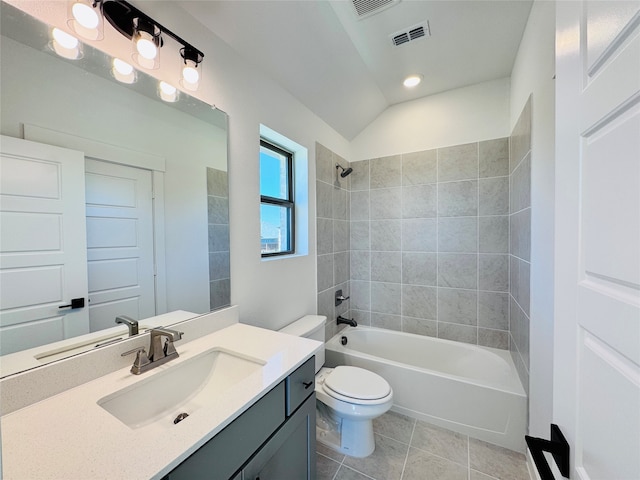 full bathroom featuring tiled shower / bath, lofted ceiling, toilet, vanity, and tile patterned flooring