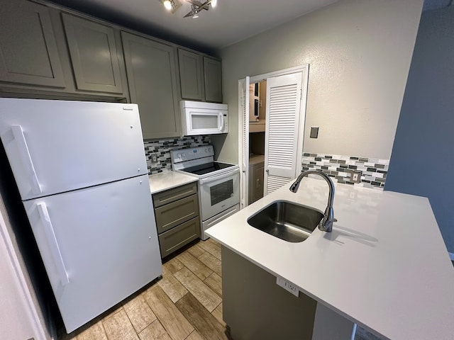 kitchen with light hardwood / wood-style flooring, kitchen peninsula, backsplash, sink, and white appliances