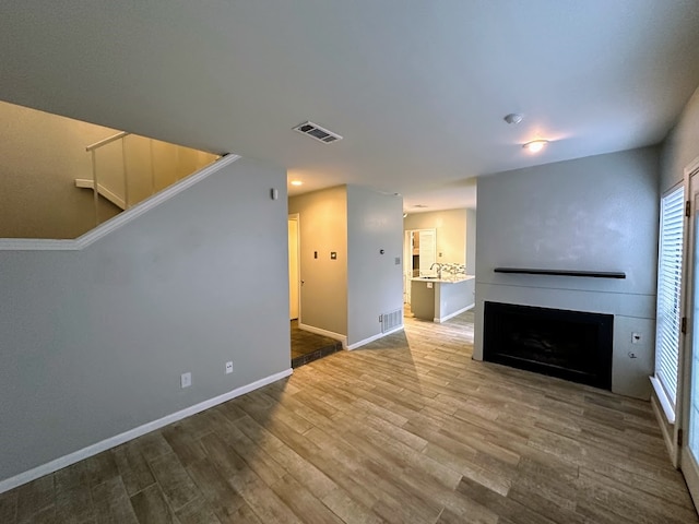 unfurnished living room featuring wood-type flooring and sink