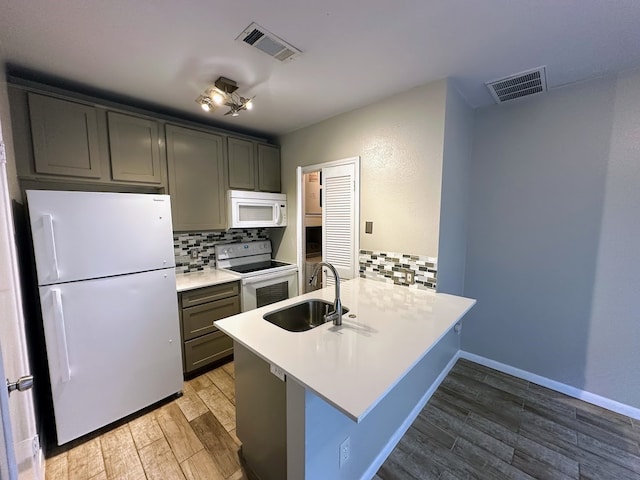 kitchen with white appliances, backsplash, sink, and kitchen peninsula