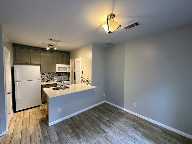 kitchen featuring white appliances, sink, backsplash, kitchen peninsula, and dark hardwood / wood-style floors