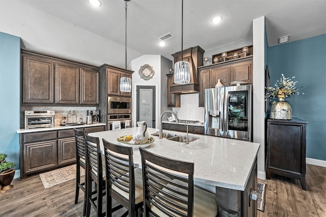 kitchen with decorative backsplash, hanging light fixtures, dark hardwood / wood-style flooring, a kitchen island with sink, and stainless steel appliances