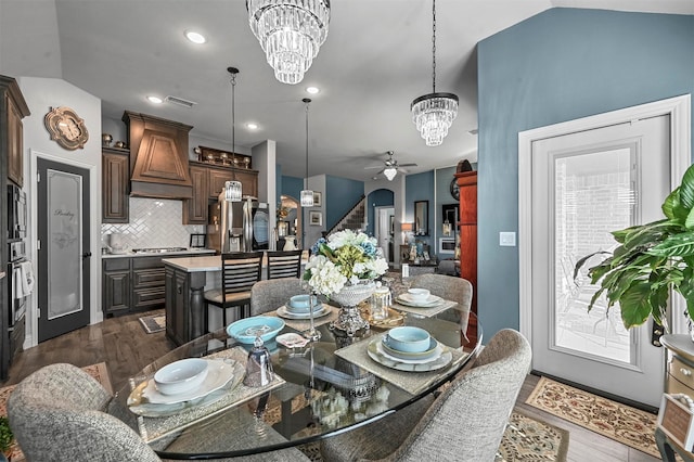 dining space featuring vaulted ceiling, ceiling fan with notable chandelier, and dark hardwood / wood-style flooring