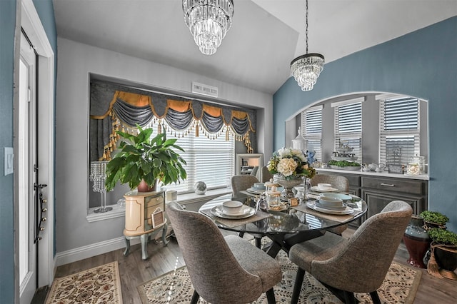 dining room featuring lofted ceiling, hardwood / wood-style floors, and a chandelier