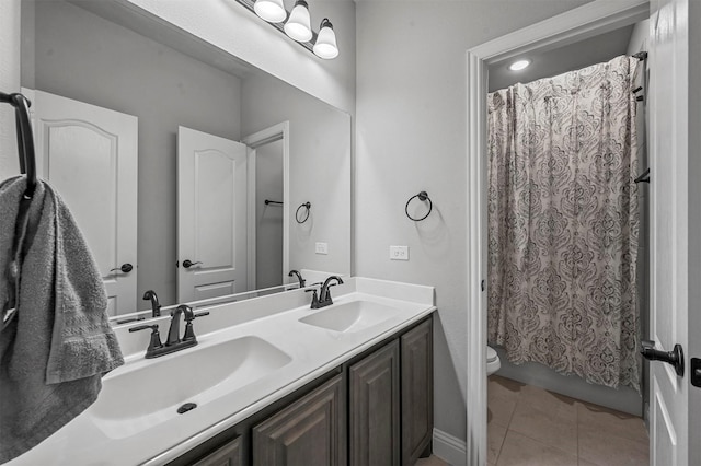 bathroom with tile patterned floors, a sink, double vanity, and toilet