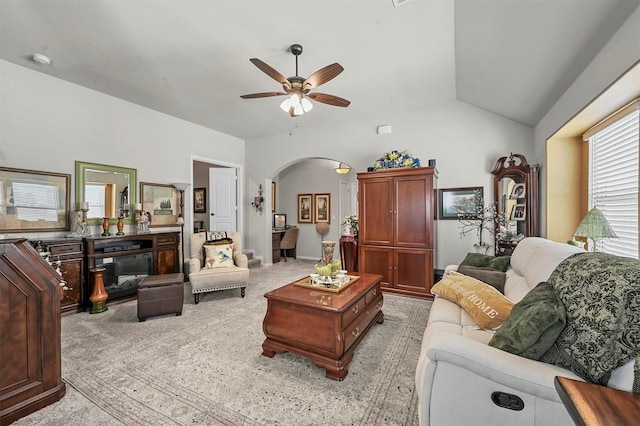 carpeted living room with ceiling fan and vaulted ceiling