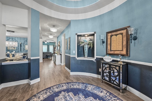 corridor with hardwood / wood-style floors and a notable chandelier