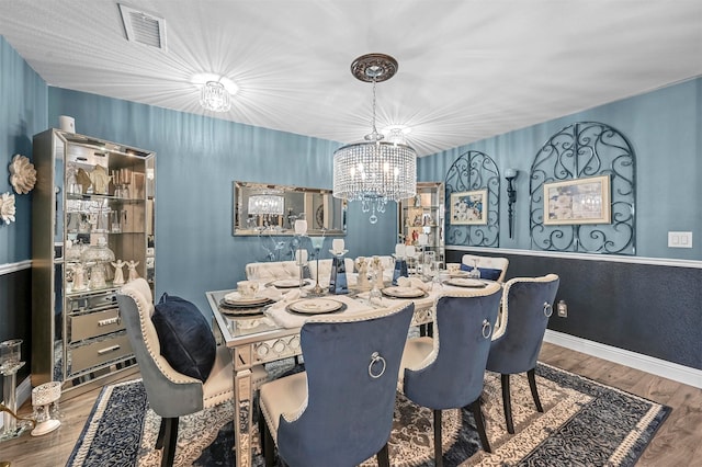 dining room with hardwood / wood-style floors and an inviting chandelier