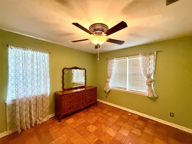 bedroom with ceiling fan, light parquet flooring, and a textured ceiling